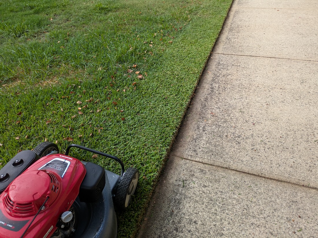a lawn after edging which is now being mowed with a commercial lawn mower